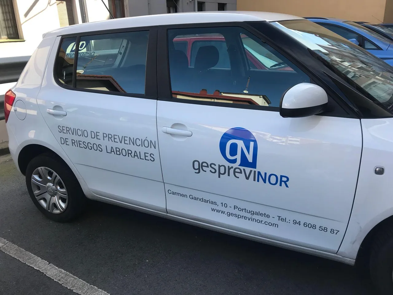 Coche de empresa con logotipo y descripción de servicios en las puertas